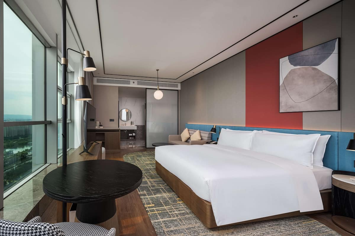 Une chambre d’hôtel moderne, dotée d’un grand lit, d’un bureau et offrant une vue sur la ville.