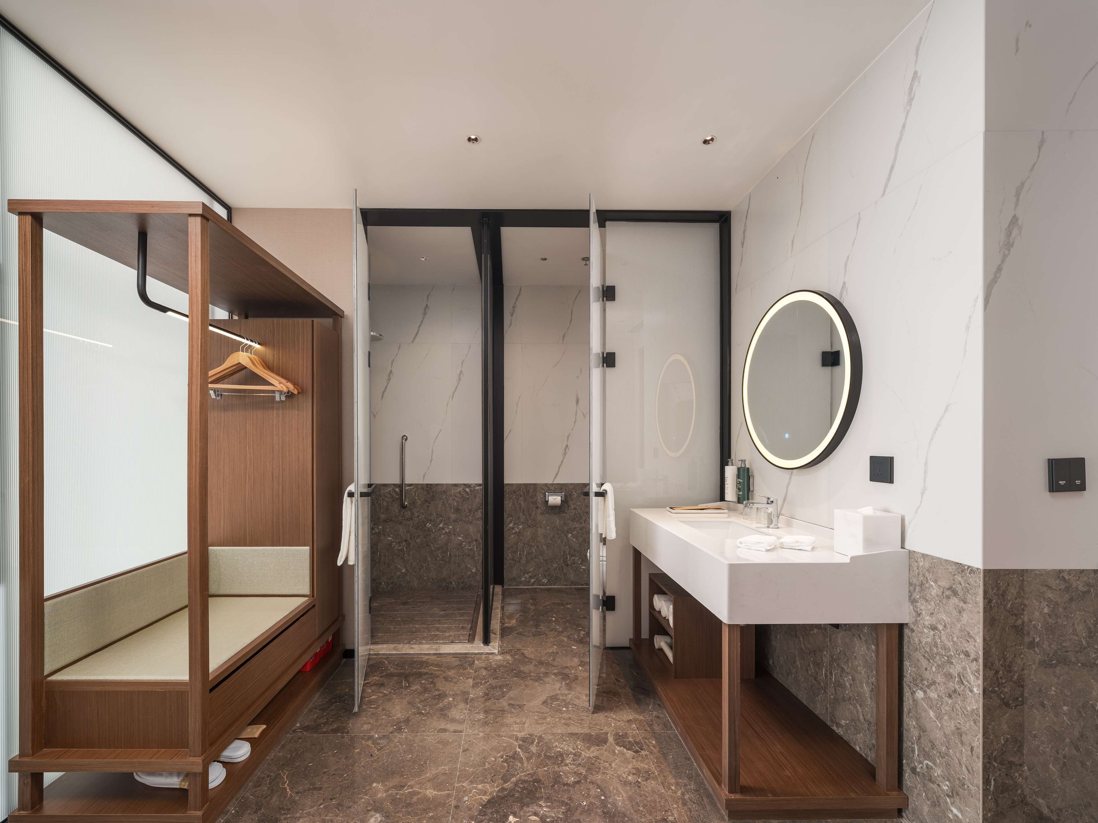 A modern bathroom with a wooden vanity, a large mirror, and a shower area.