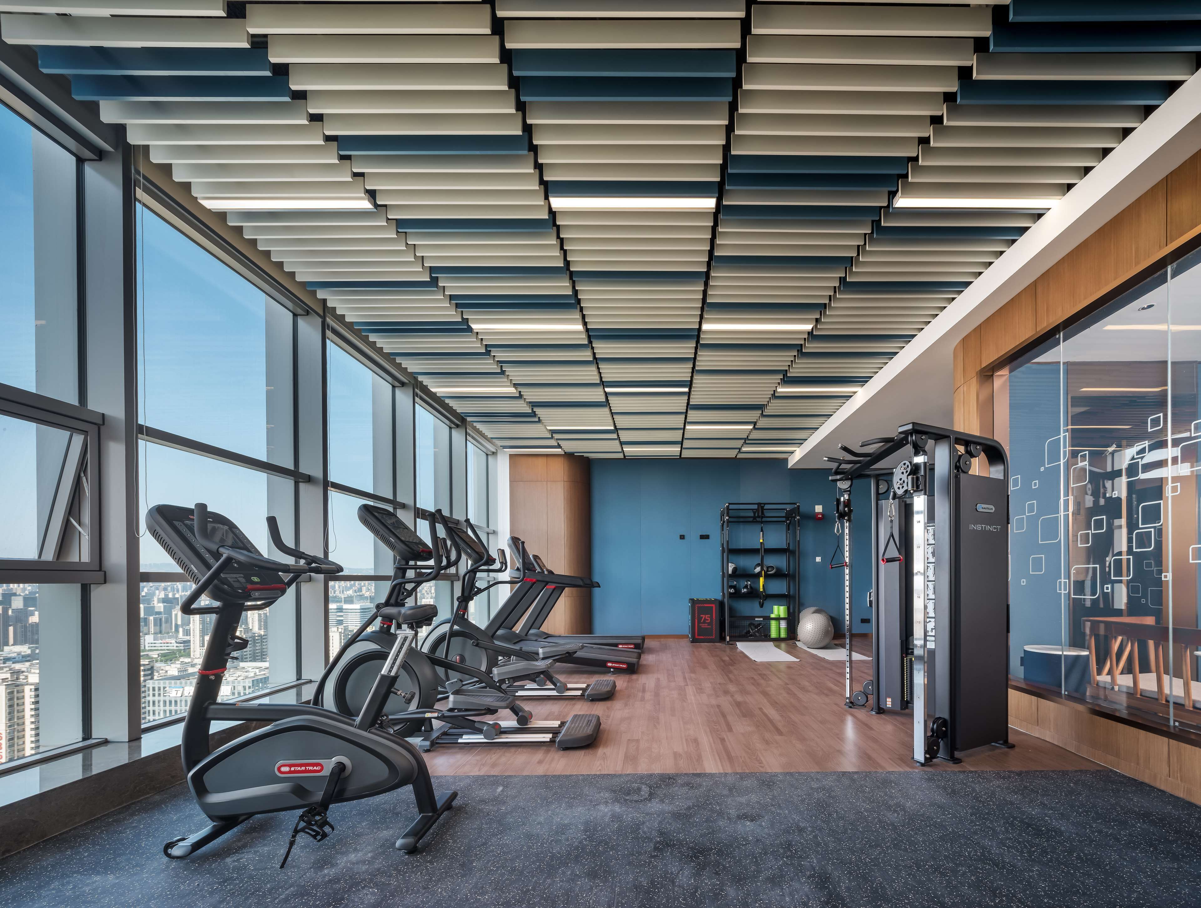 Un gimnasio moderno con cintas de correr, un banco de pesas y una zona de dominadas.