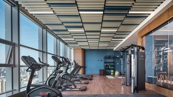 Un gimnasio moderno con cintas de correr, un banco de pesas y una zona de dominadas.
