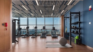Une salle de sport moderne équipée de machines de cardio, d’un support pour les exercices de squat et d’un porte-kettlebells.