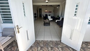 A spacious living area with a dining table and chairs, a ceiling fan, and a view of the adjacent room.