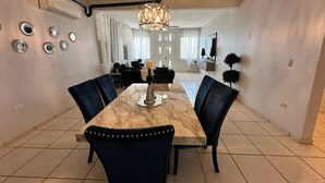 A dining area with a marble table, black upholstered chairs, and a chandelier.