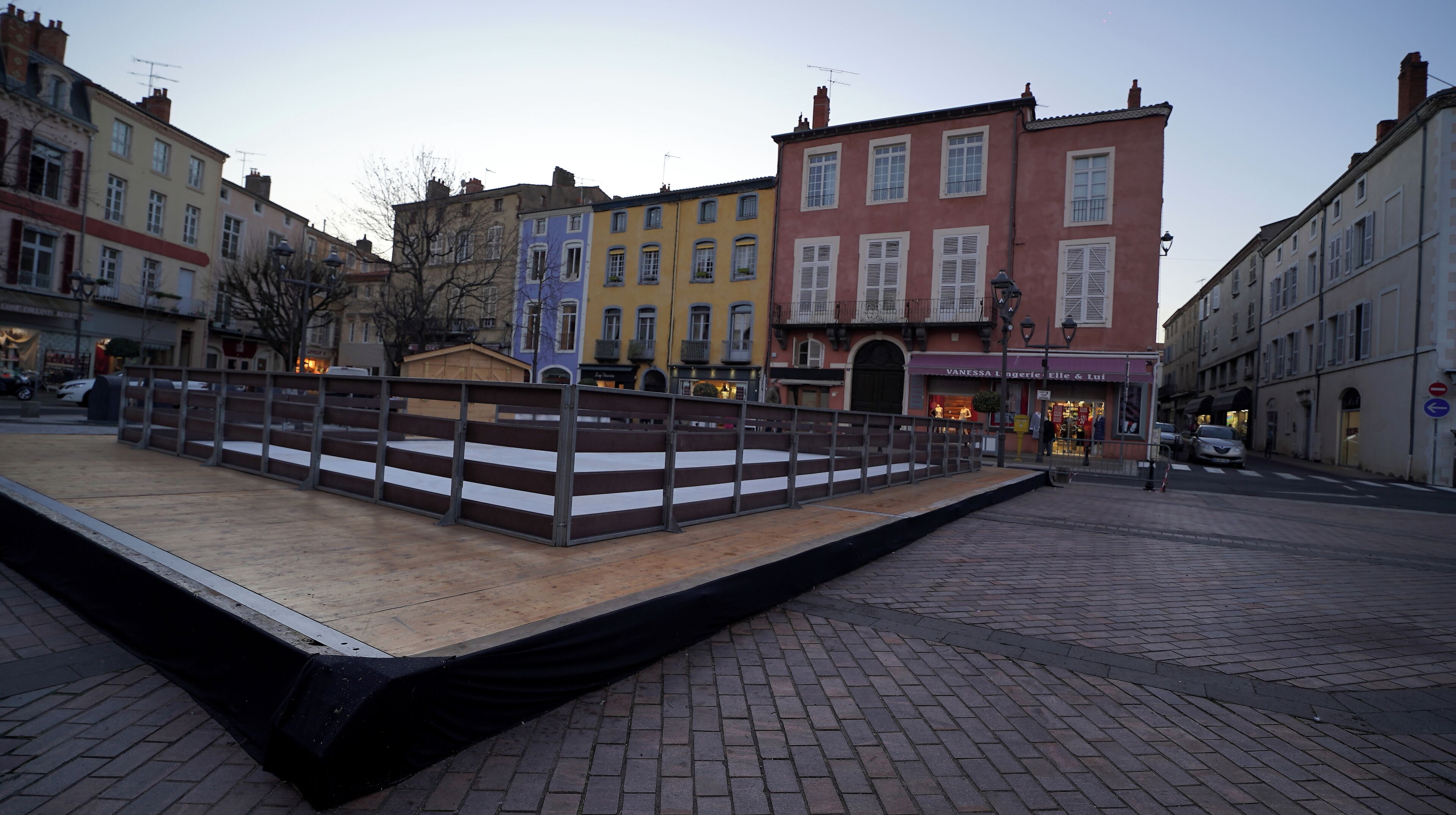 Una plaça pavimentada amb una banca de fusta i una barana metàl·lica.