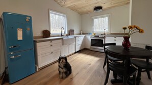 Una cocina con suelo de madera, armarios blancos, un refrigerador azul y una mesa de comedor con sillas.