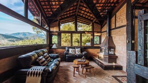 Una habitación acogedora con un sofá de cuero, una mesa redonda de madera y una chimenea.
