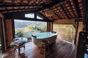 A wooden deck with a hot tub, a table with towels, and a view of the mountains. - Smart Hotel Reserva Santo Antônio do Pinhal (Santo Antonio do Pinhal)