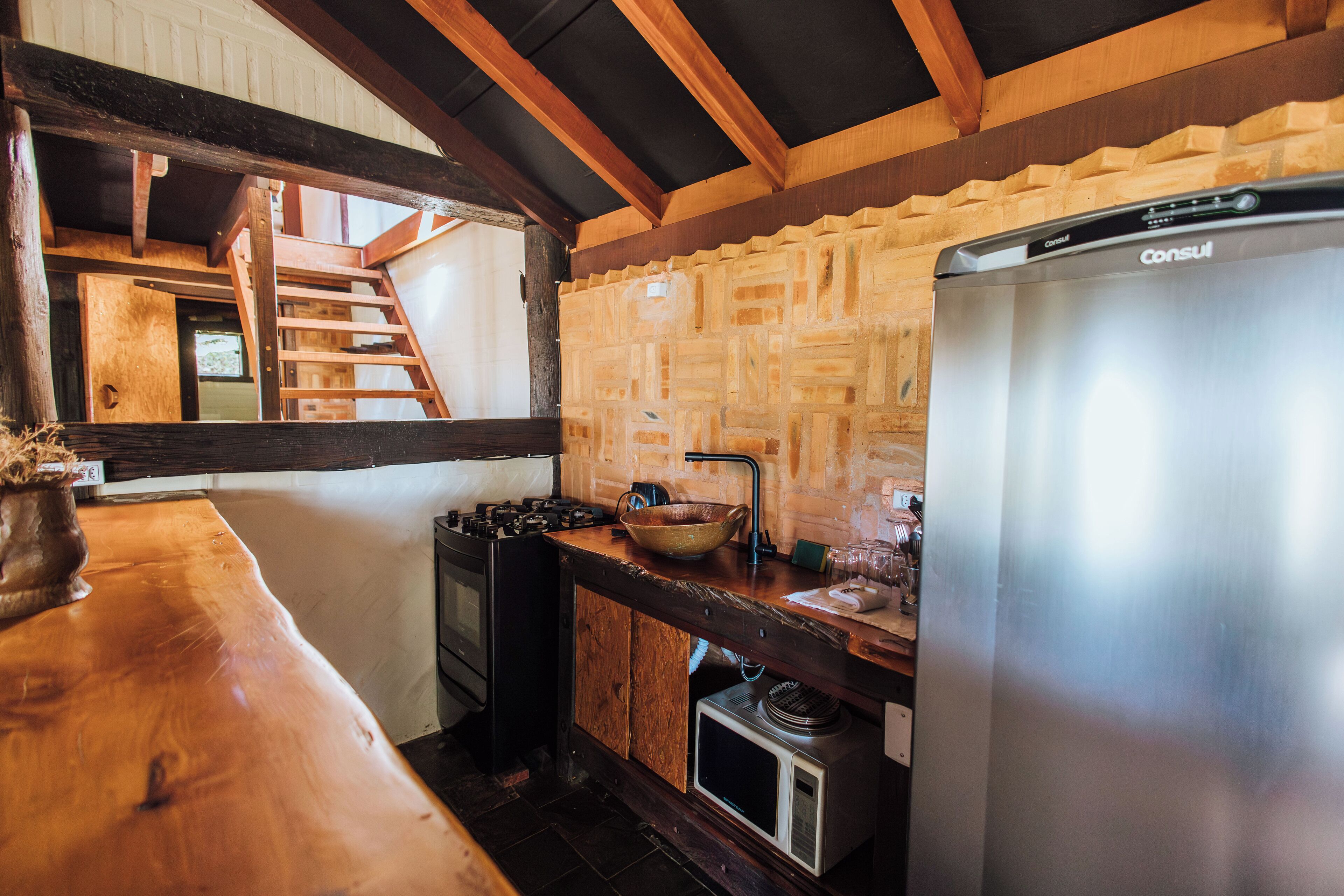 A rustic kitchen with wooden beams, a stainless steel refrigerator, and a wooden countertop.