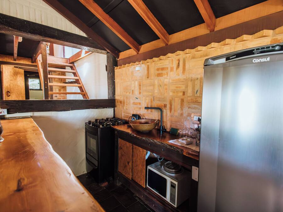 A rustic kitchen with wooden beams, a stainless steel refrigerator, and a wooden countertop.