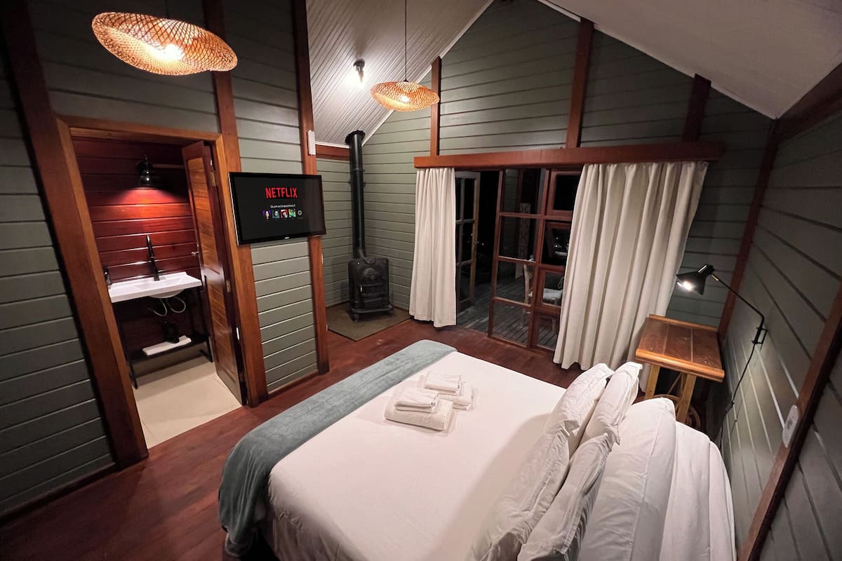 Une chambre d’hôtel équipée d’un lit, d’une télévision, d’une cheminée et d’une porte-fenêtre coulissante.