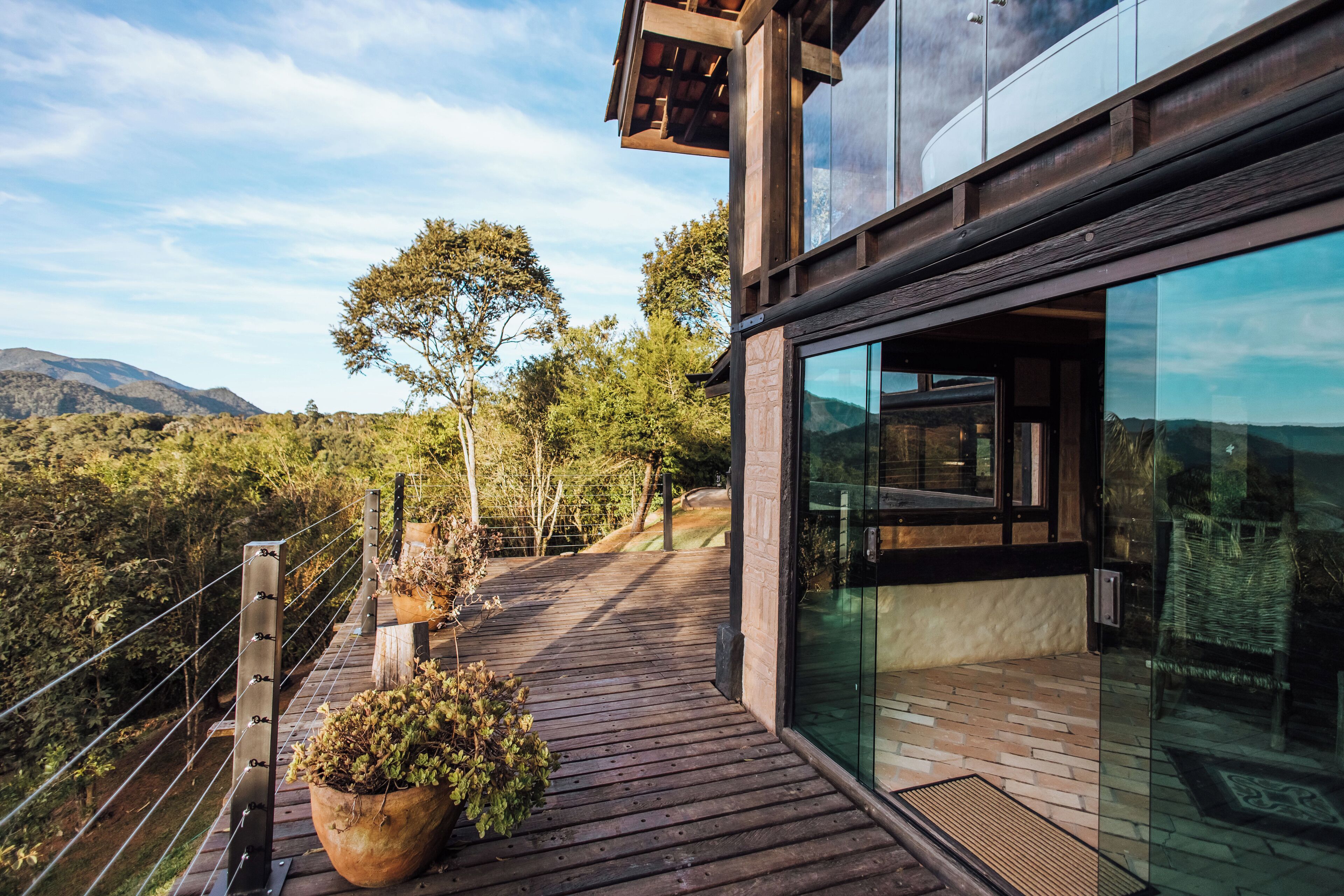 A modern building with large glass windows, a wooden deck, and a view of a mountainous landscape.