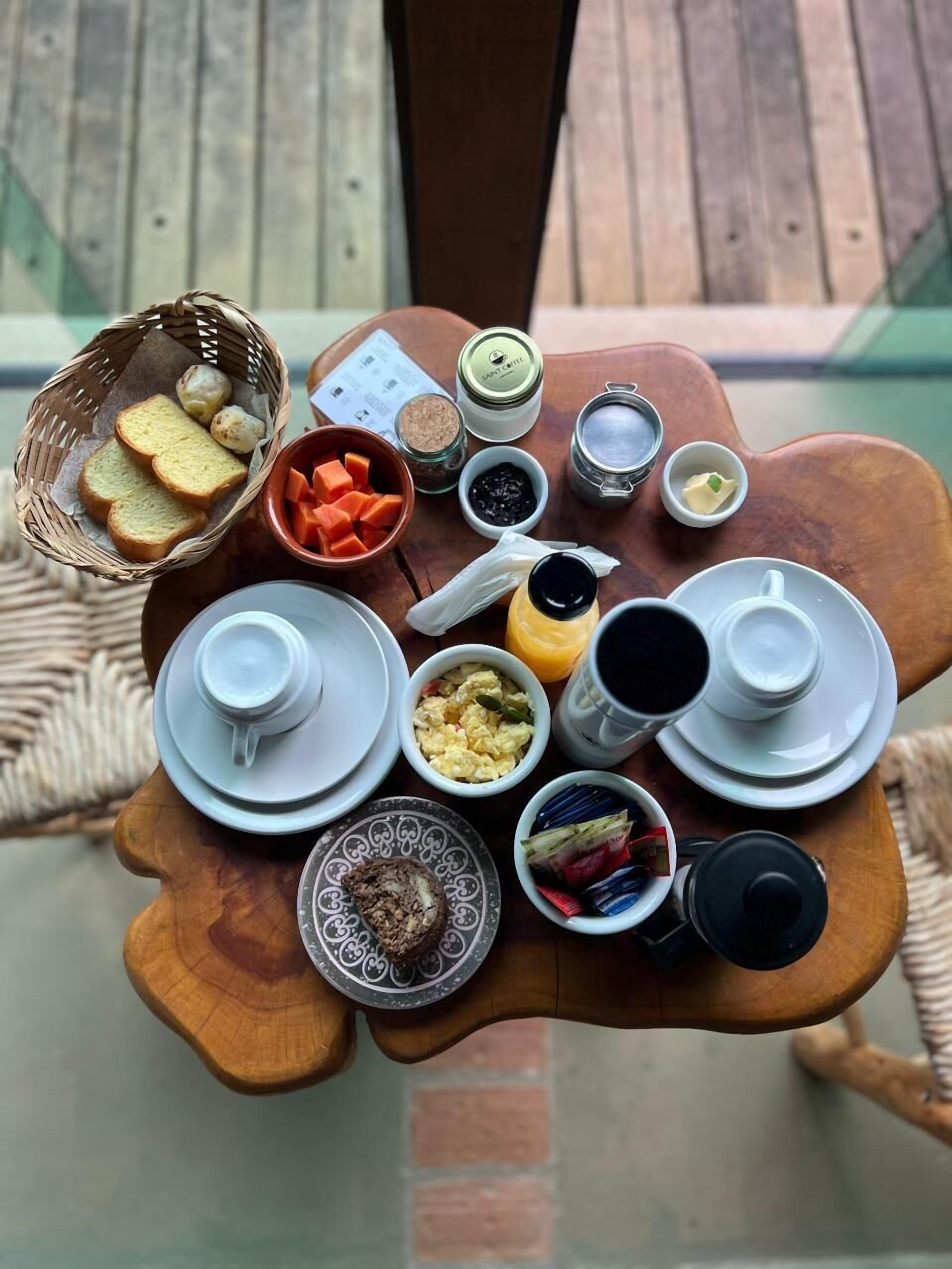 Una mesa de madera con diversos alimentos para el desayuno, como pan, huevos y salsas.