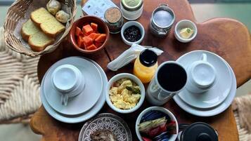 Una mesa de madera con diversos alimentos para el desayuno, como pan, huevos y salsas.