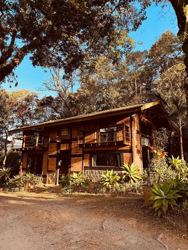 A rustic wooden building with a balcony, surrounded by lush greenery and trees. - Smart Hotel Reserva Santo Antônio do Pinhal (Santo Antonio do Pinhal)