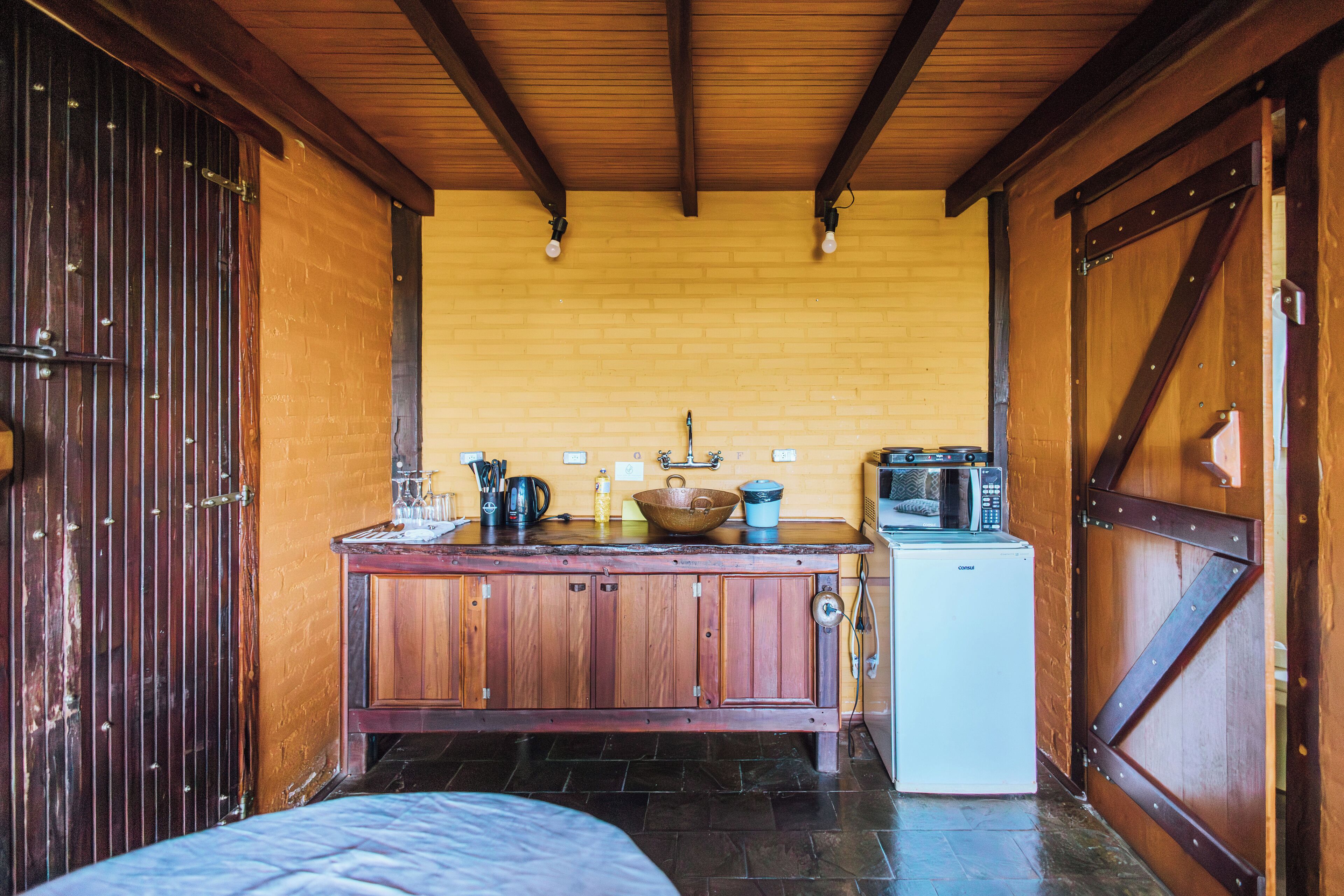 A rustic kitchen with wooden cabinets, a sink, a microwave, and a coffee maker.