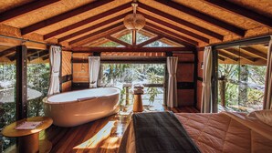Una habitación amplia con una bañera grande, una cama y vistas al exterior.