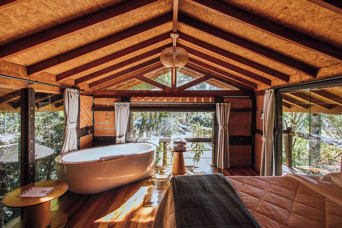 Une pièce spacieuse avec une grande baignoire, un lit et une vue sur l’extérieur.