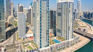 A high-rise hotel with multiple floors, a swimming pool, and a waterfront view. - Vogue | DAMAC Maison Privé | Near Dubai Mall (Dubai)