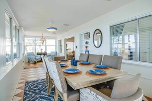 A dining area with a wooden table set for six, surrounded by chairs.
