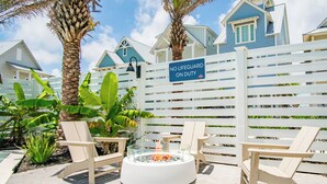 Un espace aménagé au bord de la piscine, comprenant un foyer, des chaises longues et un panneau indiquant l’absence de sauveteur.