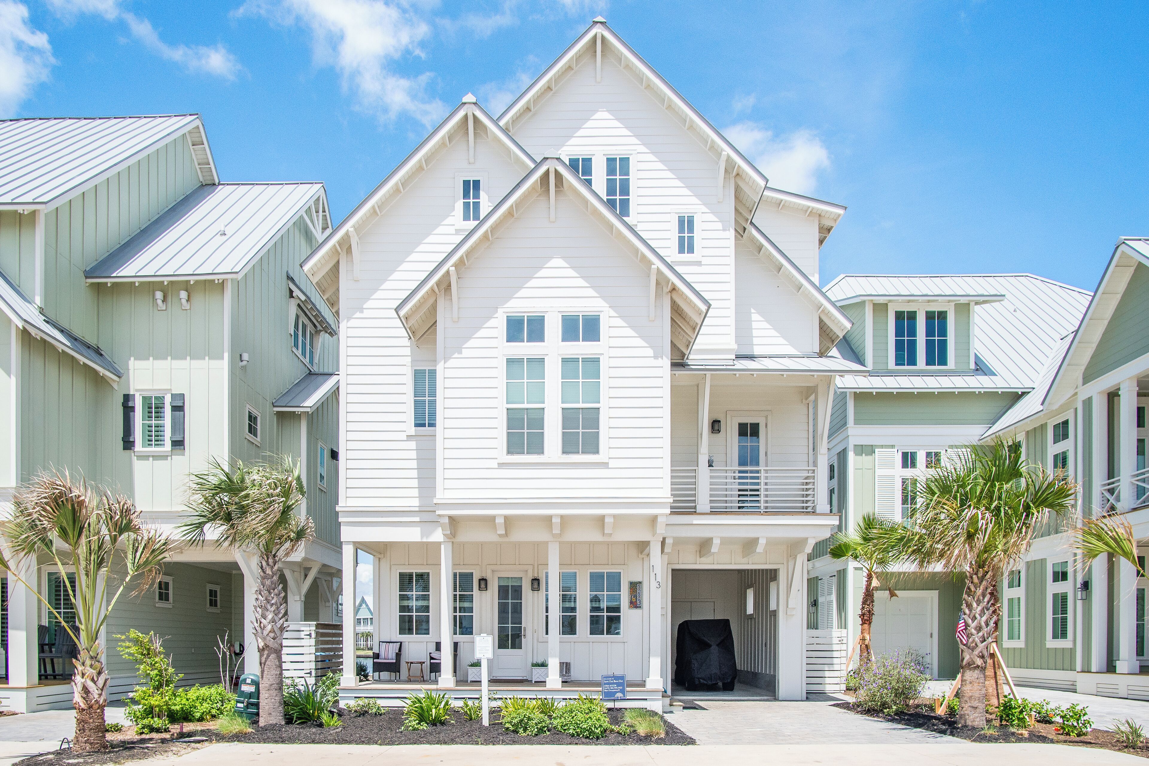 A multi-story residential building with a central entrance, multiple windows, and a covered porch area.