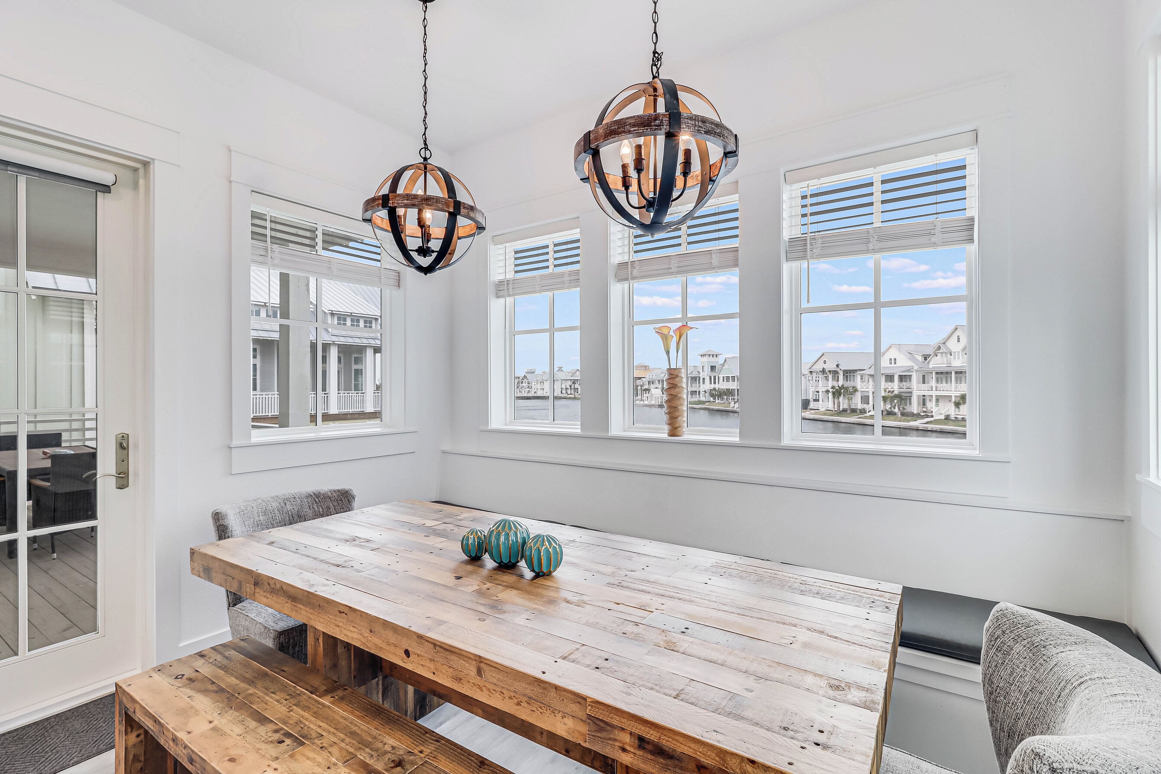A dining area with a wooden table, benches, and a view of the city through large windows.