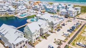 Un quartier résidentiel situé sur la côte, comprenant plusieurs maisons, une piscine et un port de plaisance.