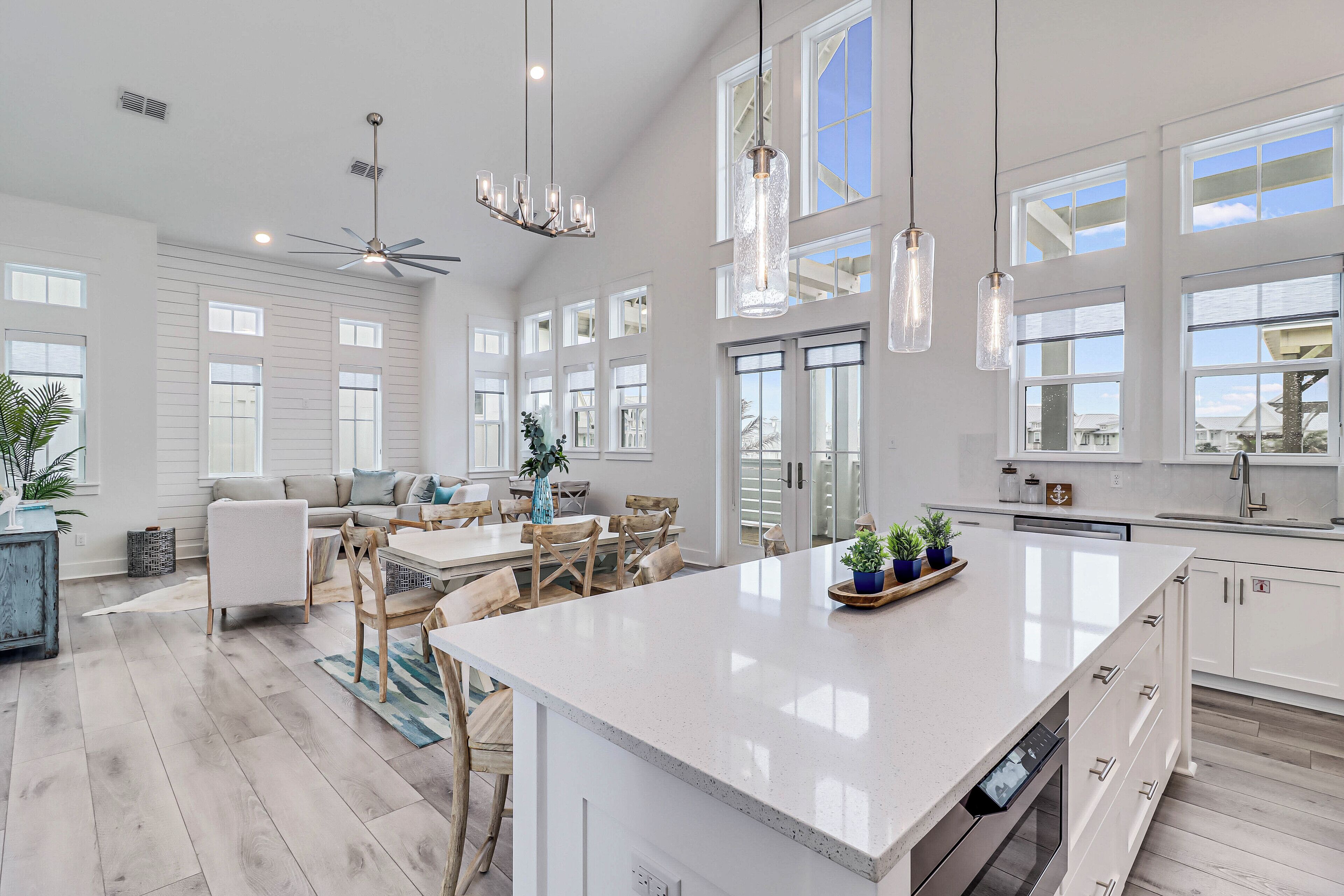 A spacious kitchen with a large island, white cabinetry, and pendant lighting.