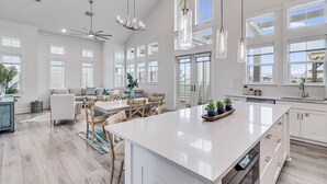 A spacious kitchen with a large island, white cabinetry, and pendant lighting. - Beach Barn 108 BAR (Port Aransas)