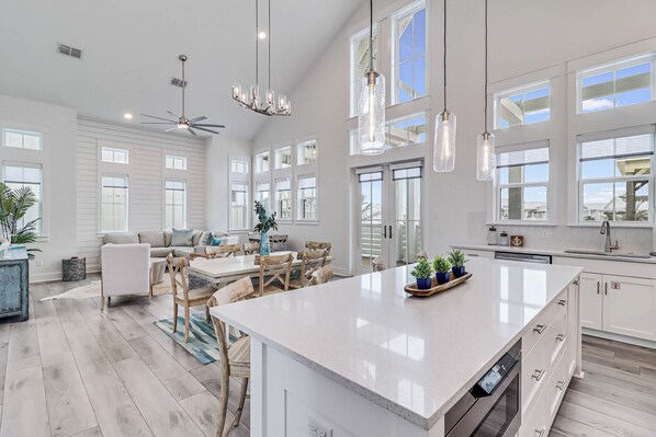 A spacious kitchen with a large island, white cabinetry, and pendant lighting.