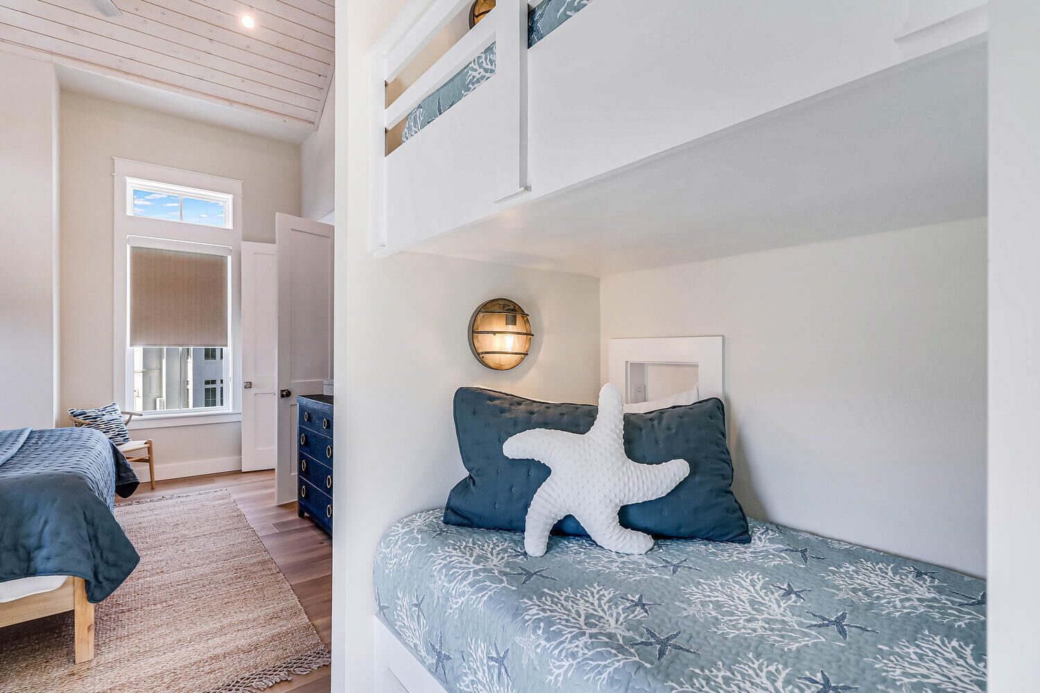 A bedroom with a bunk bed, a nightstand, a dresser, and a window with blinds.