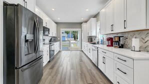 A modern kitchen with stainless steel appliances, white cabinetry, and a herringbone-patterned backsplash. - 6 BR, 4BA Franklin, IN Home (Franklin)