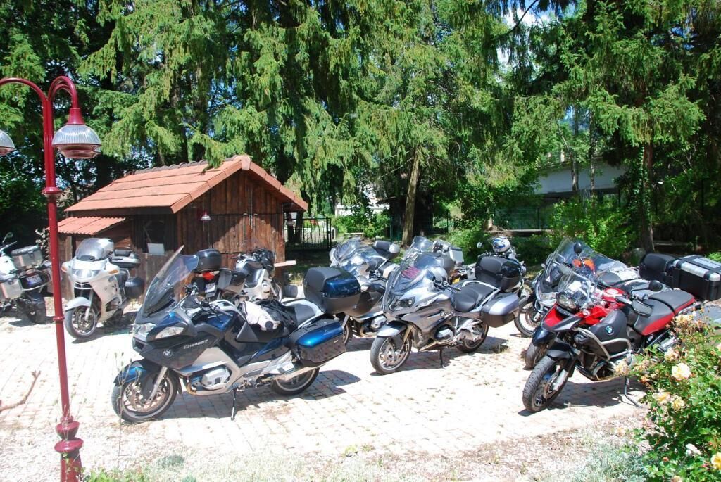 Una fila de motocicletas estacionadas en un área de estacionamiento, con un edificio de madera al fondo.