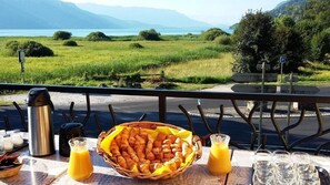 A table with croissants, juice, and a view of a lake and mountains. - Auberge de Portout (Chanaz)