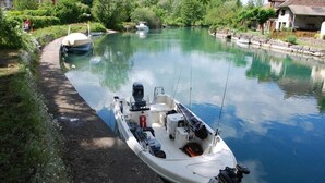 A narrow waterway with boats docked on the banks. - Auberge de Portout (Chanaz)