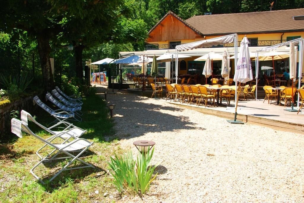 An outdoor seating area with tables and chairs, a covered patio, and a building with a sloped roof.