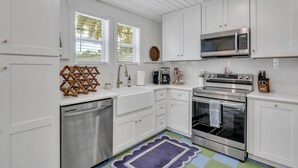 Una cucina moderna con mobili bianchi, elettrodomestici in acciaio inossidabile e un tappeto colorato.
