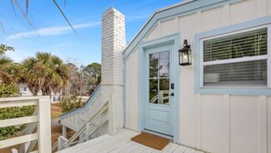 Un bâtiment blanc avec une porte bleue, un escalier blanc et une balustrade blanche.