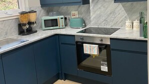 Eine moderne Küche mit dunkelblauen Schränken, einer Mikrowelle, einem Toaster und einem Einbauofen.