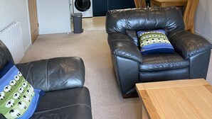 Ein gemütlicher Wohnbereich mit einer Couch, einem Holztisch und einer Küche im Hintergrund.