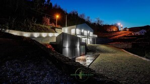 A modern building with a glass facade, situated on a hillside with a view of the surrounding landscape. - Casa do Barbeiro | Pool | River Minho Views | Agro-tourism (Melgaço)