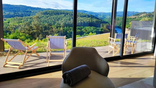 A modern room with large windows offering a scenic view of a forested valley. - Casa do Barbeiro | Pool | River Minho Views | Agro-tourism (Melgaço)