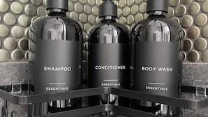 Three bottles of shampoo, conditioner, and body wash on a metal shelf against a textured wall. - Squareview Stays - Modern Apartment On the Square (Indianola)