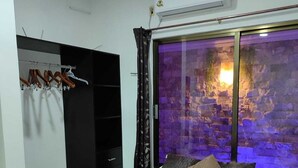 A bedroom with a bed, a wardrobe, and a window with a stone wall view. - Departamentos Chan Kiin (Valladolid)