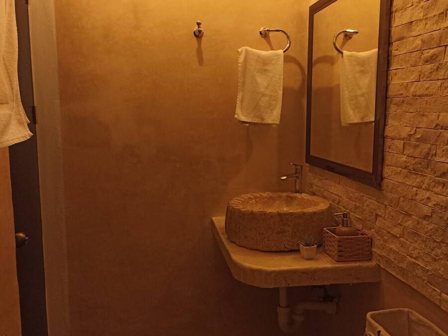 Un baño con un lavamanos de piedra, un espejo y un ventanal con vistas.