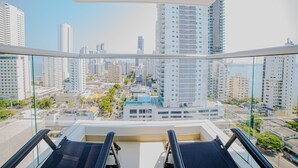 Apartamento moderno de altura con balcón que cuenta con dos sillones de descanso negros, vistas a la ciudad y arquitectura contemporánea.