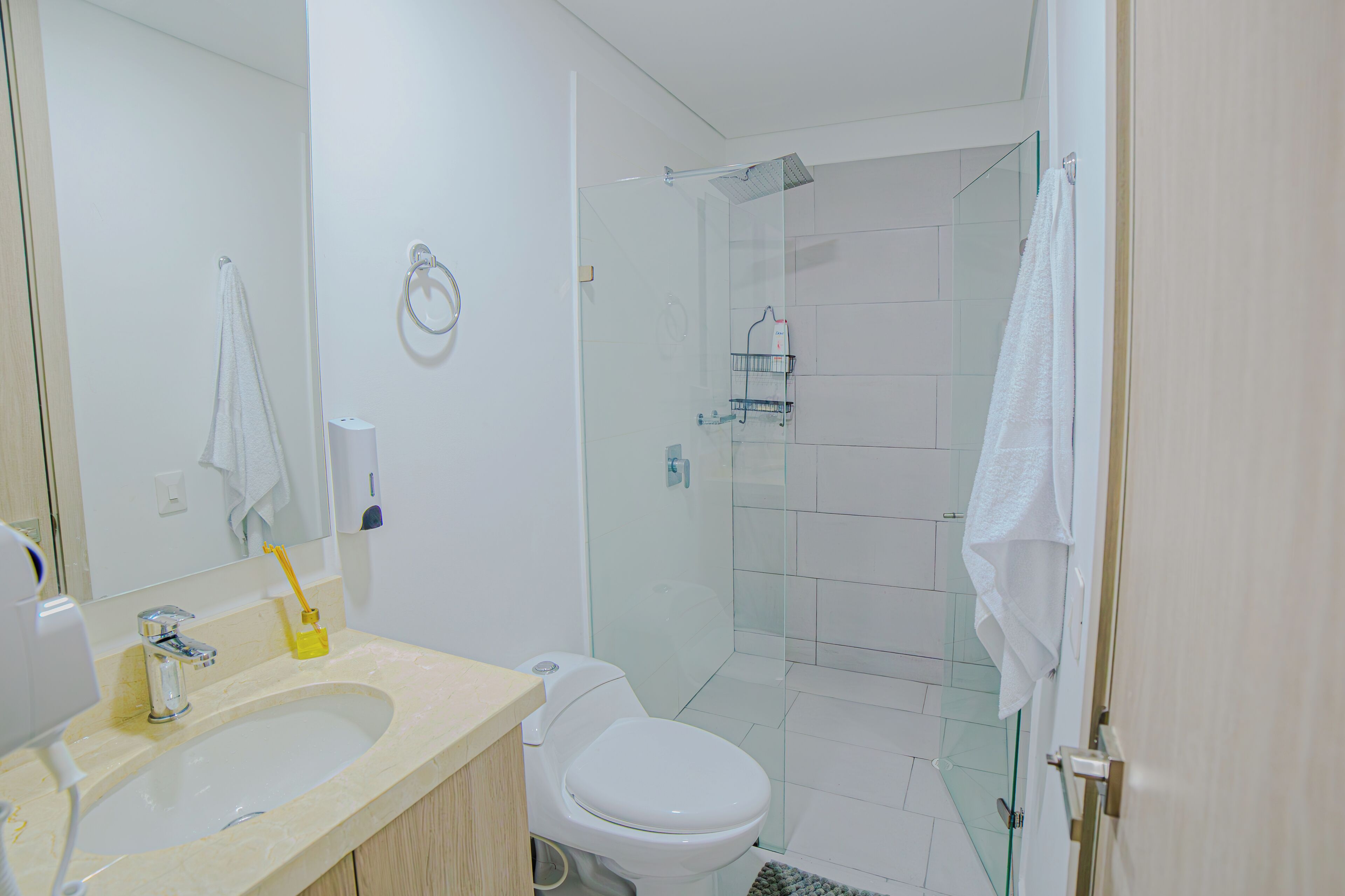 A modern bathroom with a glass shower enclosure, a sink with a mirror, and a toilet.