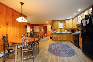 Un intérieur en bois comprenant une table à manger, des chaises, un coin cuisine et un réfrigérateur.