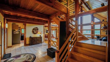 A spacious interior with a wooden staircase, a kitchen area, and a dining space.
