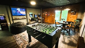 Una habitació amb taula de futbolí, televisió i jocs recreatius.